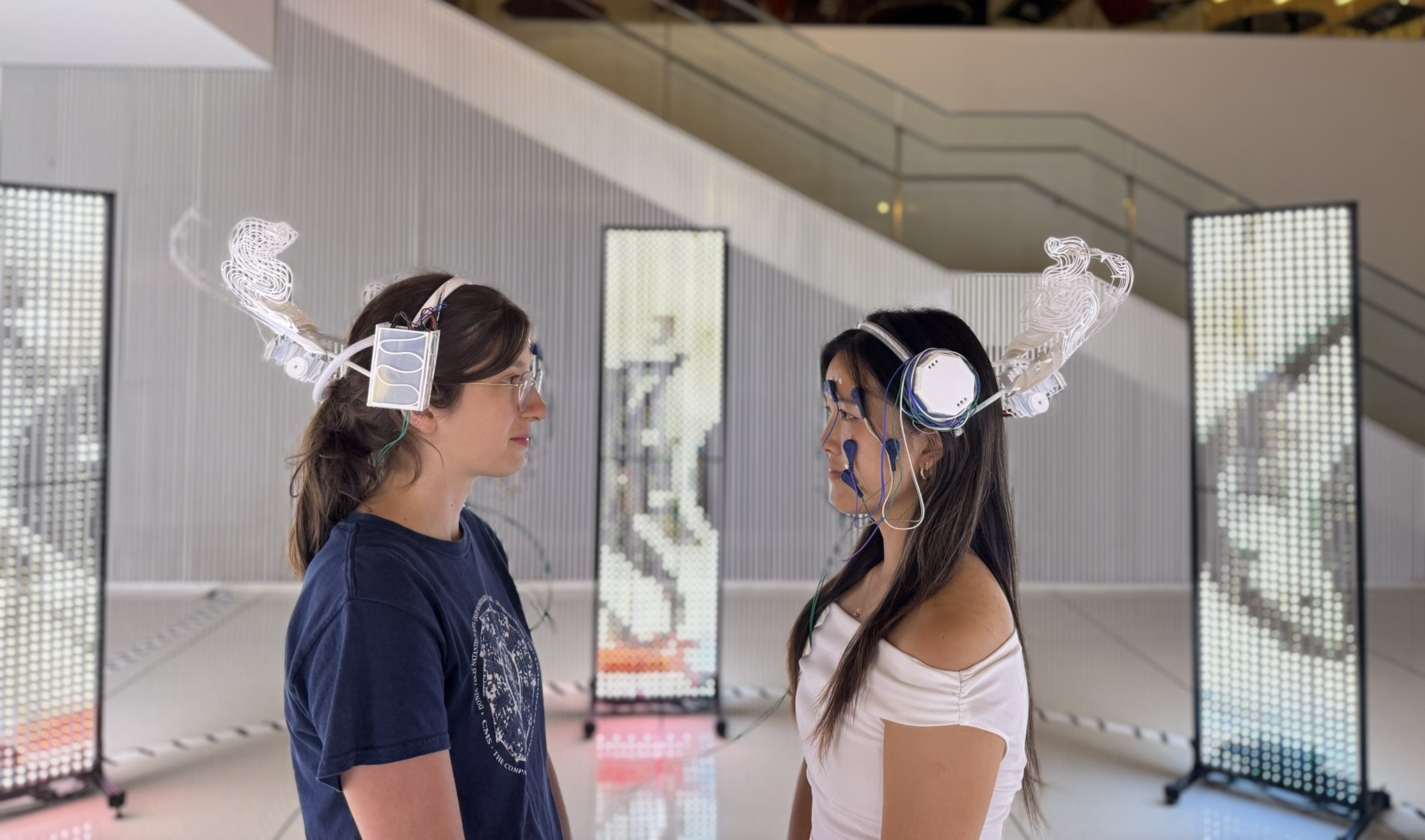 Two people facing each other wearing Somatic Bloom headpieces